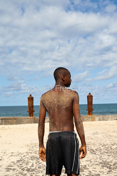 São Tomé and Principe - São Tomé - A boy with a sand covered back on the Marginal 12 Julho, Sao Tome 