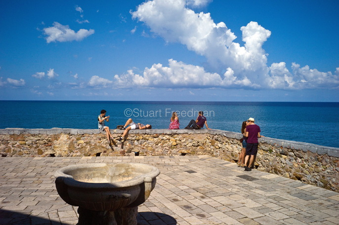 Italy - Cefalu - Tourists photograph, chat and kiss on the sea wall