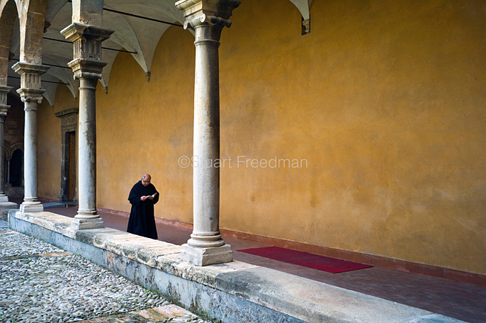 Italy - Palermo - A priest reads as he walks through the cloisters in the courtyard of the St Augustino church