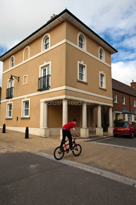 UK - Dorset - A boy rides his bicycle past a traditionally styled building in Poundbury. Poundbury on Duchy of Cornwall land is Prince Charles' attempt to create an urban extension to Dorchester famed for Its pastiche of traditional architecture. 
