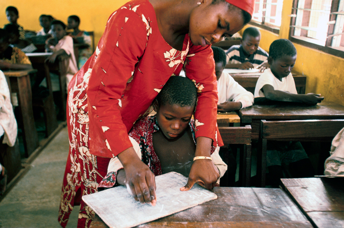 Ghana - Tamale - A street child is helped to read in a school by a teacher in a school run by the Youth Alive project